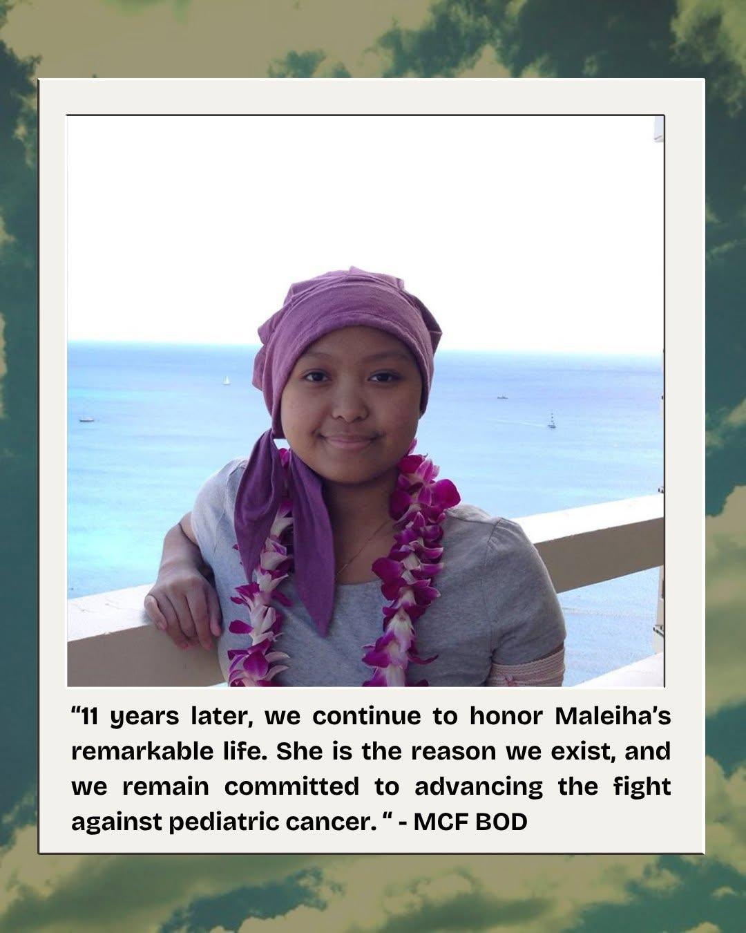 Maleiha in a purple headscarf and an orchid lei, smiling in front of the ocean in Hawaii.