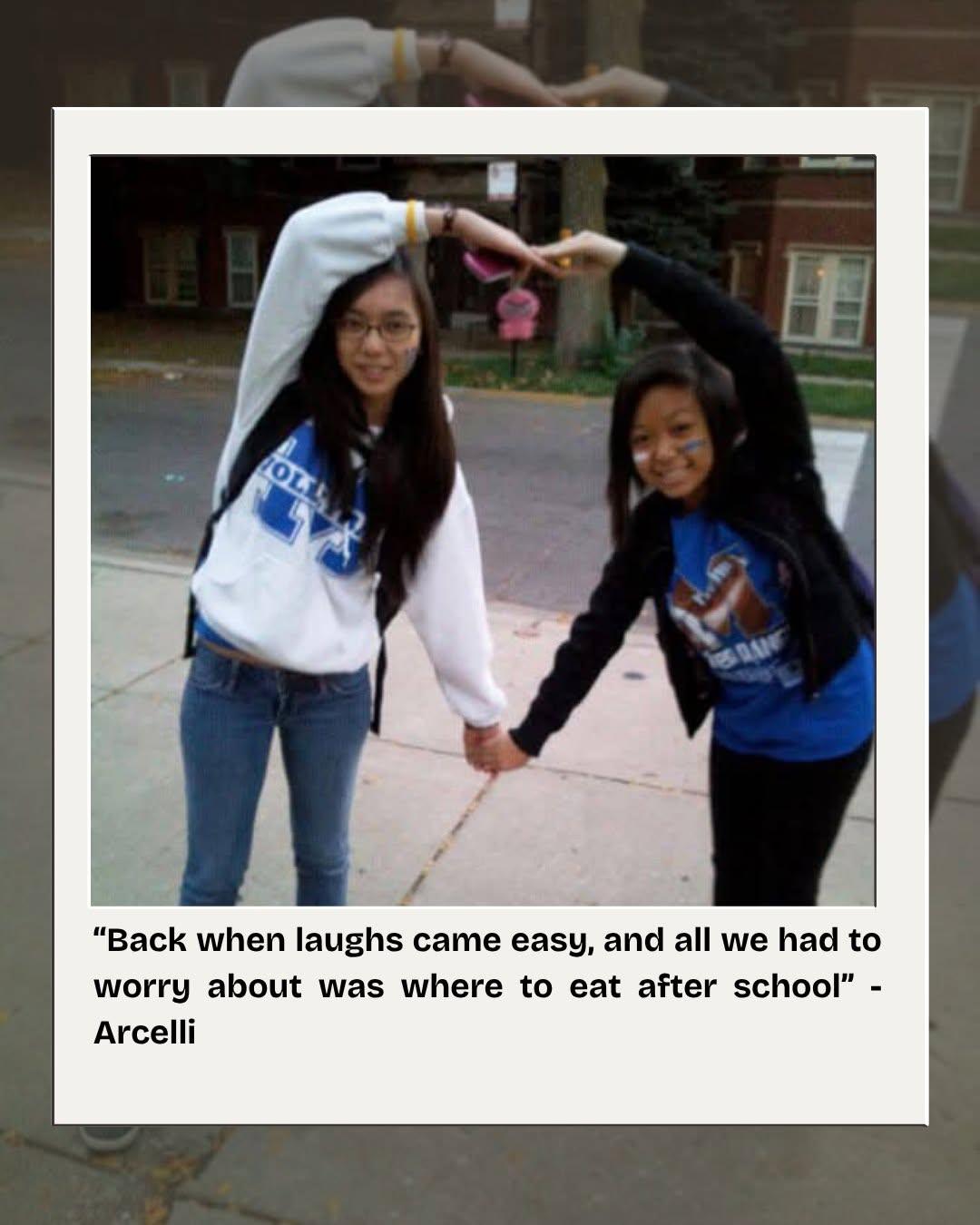 Maleiha and a friend holding hands and arching their arms overhead on a sidewalk after school.